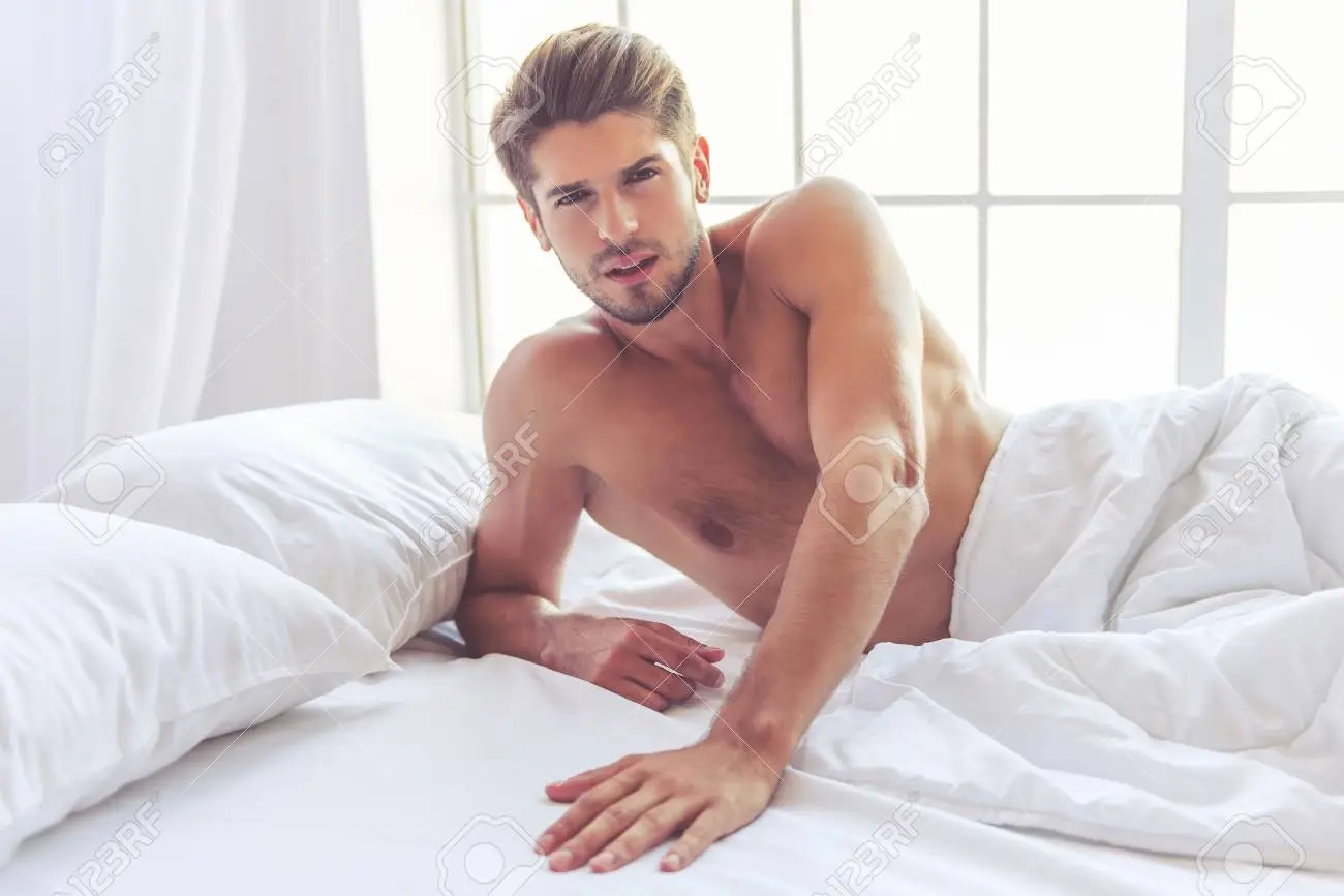 sexy-young-man-is-looking-at-camera-while-lying-in-bed